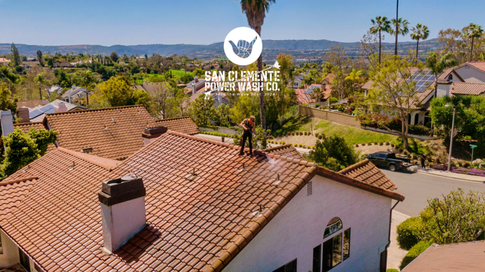 Aerial view of a technician soft washing a Spanish tile roof above the Laguna hills